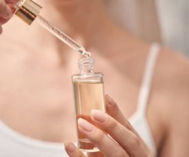 Cropped photo of a Caucasian lady holding a dropper and a bottle of oil in her hands