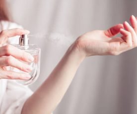 girl in a white dress sprays herself perfume on her wrist