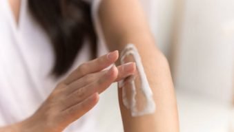 Close up hand of young Asian woman applying skin care cream lotion on her arm. Woman beauty self care cosmetic caring routine concept.